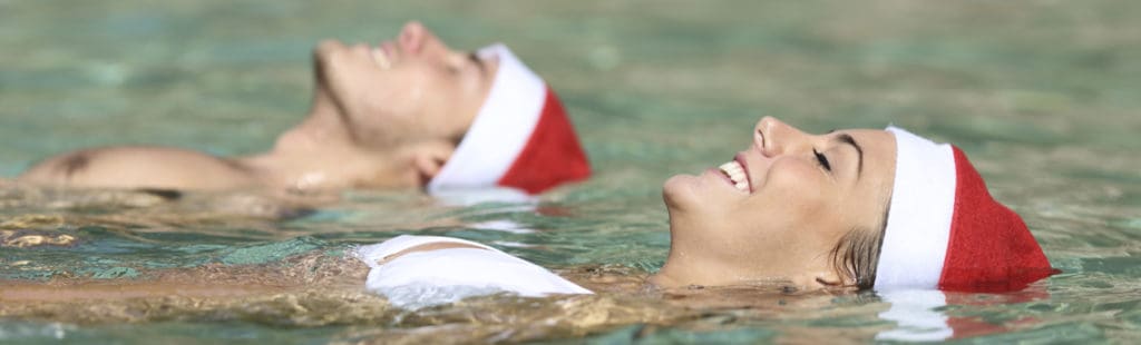 Things to do on Maui in winter: couple swimming in the ocean with santa hats on