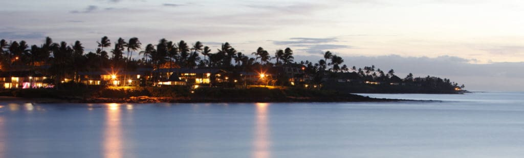 Where to stay on Maui: evening on Napili Bay with lights on at condos